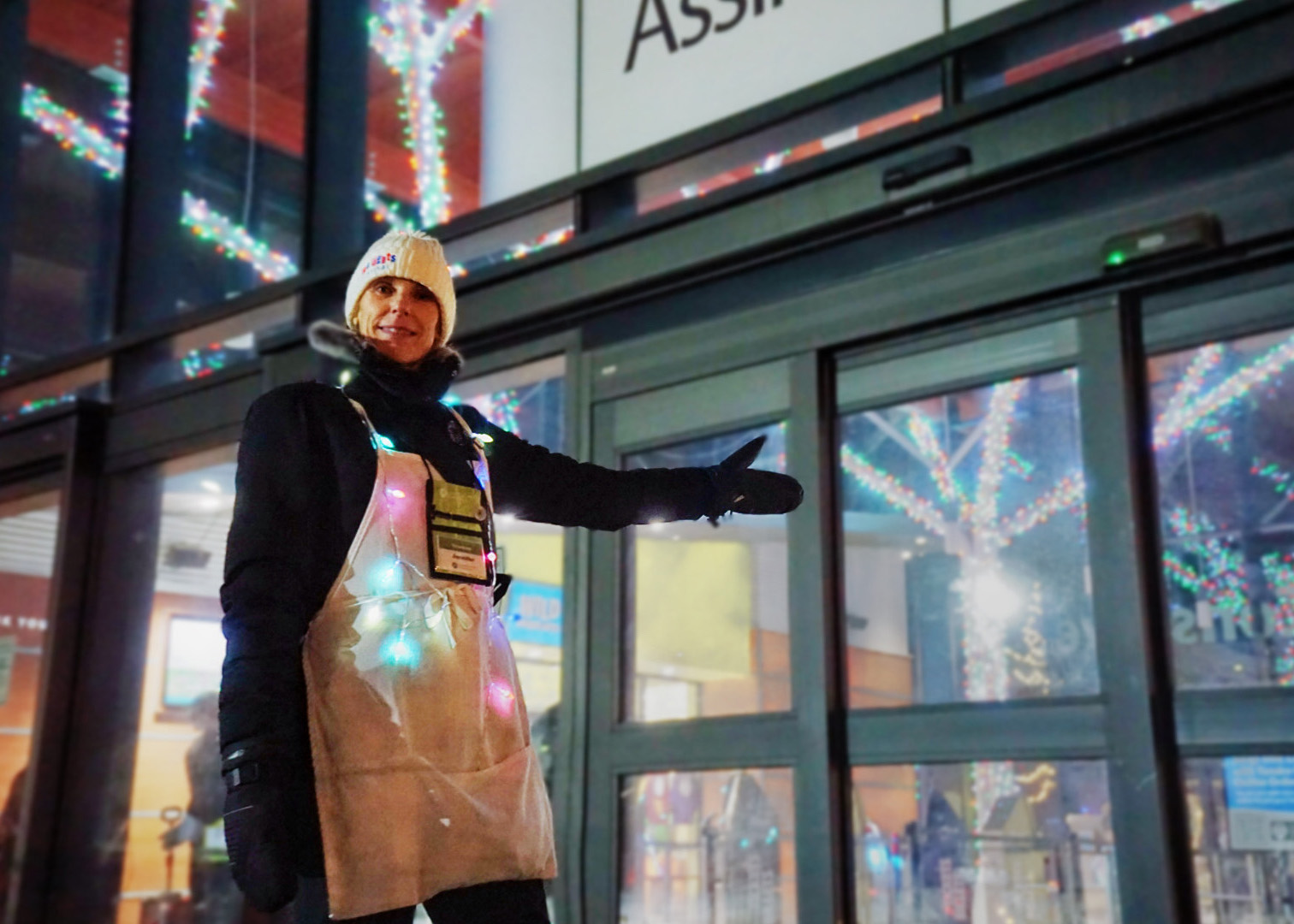 A volunteer gestures towards an entrance welcoming you to Zoo Lights